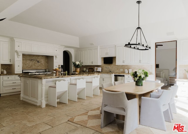 kitchen featuring a kitchen island, stainless steel dishwasher, backsplash, and white cabinets