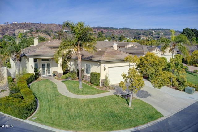 view of front of home featuring a front yard, a garage, and french doors