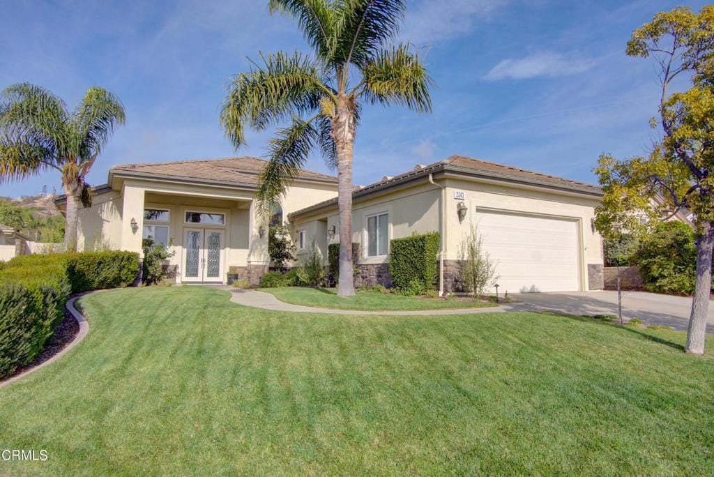 view of front of house featuring a front lawn, a garage, and french doors