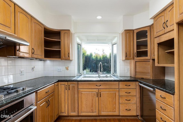 kitchen featuring decorative backsplash, sink, dark stone counters, and oven