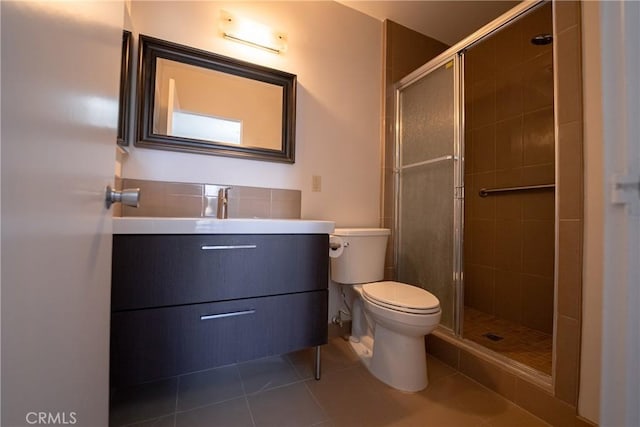 bathroom featuring toilet, tile patterned flooring, a shower with door, and vanity