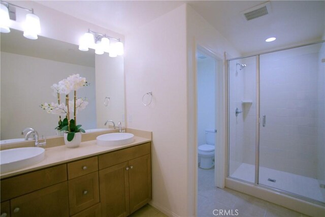 bathroom with toilet, walk in shower, vanity, and tile patterned flooring