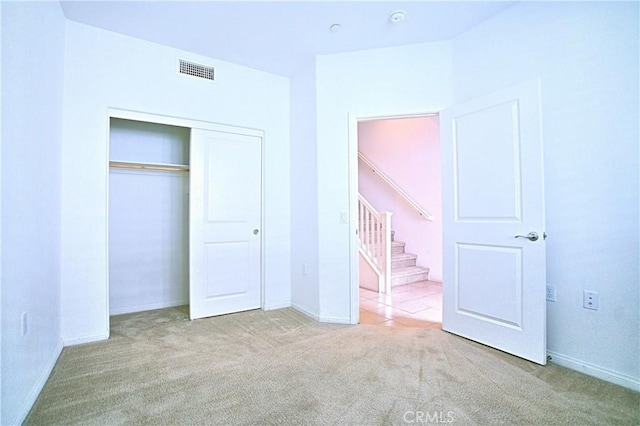 unfurnished bedroom featuring light colored carpet and a closet