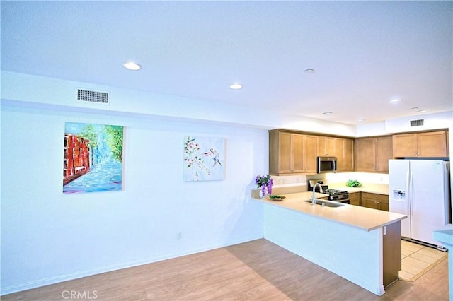 kitchen featuring sink, appliances with stainless steel finishes, light hardwood / wood-style flooring, and kitchen peninsula