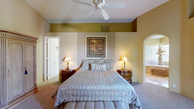 bedroom featuring ceiling fan, light colored carpet, and ensuite bath