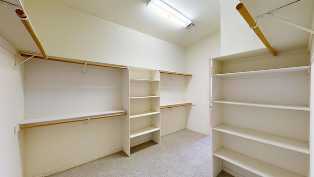 walk in closet with light colored carpet and lofted ceiling