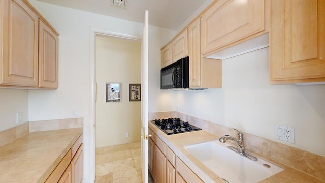 kitchen with sink, light brown cabinets, and black appliances