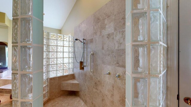 bathroom featuring a healthy amount of sunlight, lofted ceiling, and tiled shower