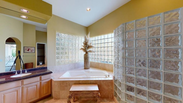 bathroom featuring vanity, tile patterned floors, and tiled tub