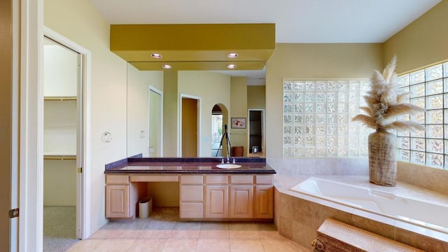 bathroom with tiled bath, tile patterned flooring, and vanity