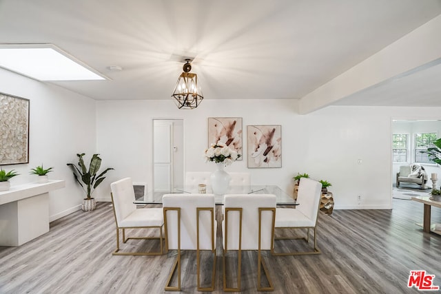 dining space featuring hardwood / wood-style floors, a skylight, and an inviting chandelier