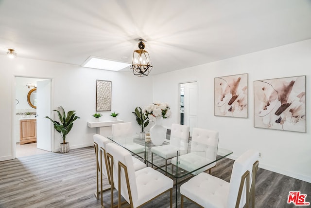 dining room with hardwood / wood-style floors, a skylight, and a notable chandelier