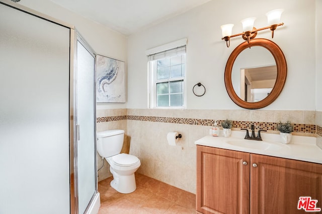 bathroom with toilet, vanity, tile patterned flooring, tile walls, and an enclosed shower