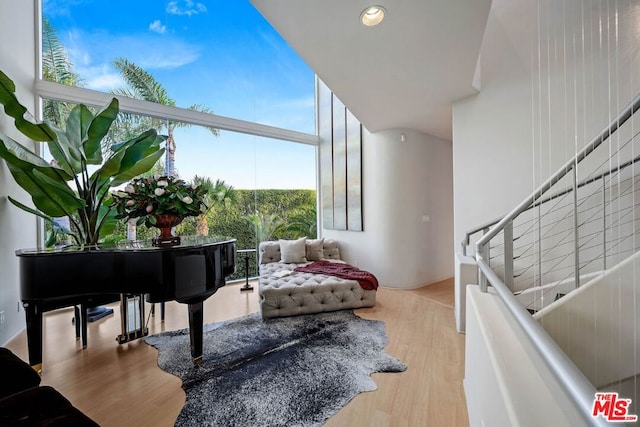 living area with a towering ceiling and hardwood / wood-style flooring