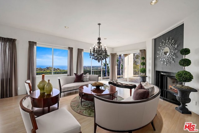 living room with a fireplace, a notable chandelier, and light hardwood / wood-style floors