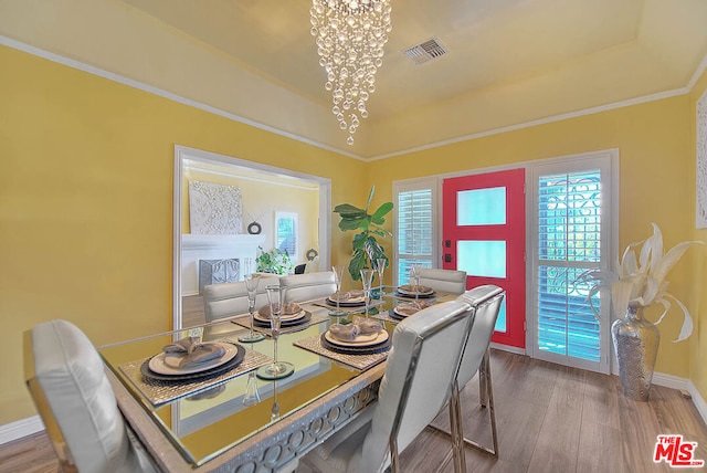 dining room with an inviting chandelier, hardwood / wood-style floors, and a tray ceiling