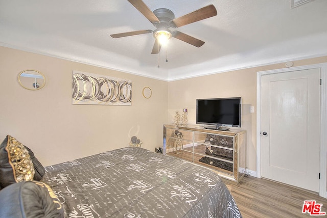 bedroom featuring ceiling fan, crown molding, and hardwood / wood-style flooring