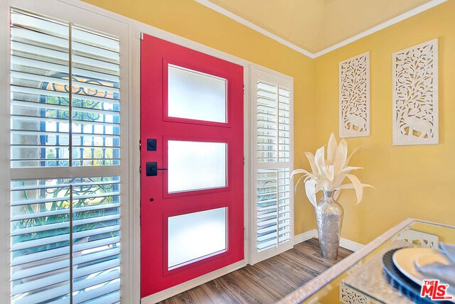 entryway with ornamental molding and hardwood / wood-style floors