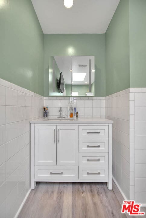 bathroom featuring tile walls, wood-type flooring, and vanity