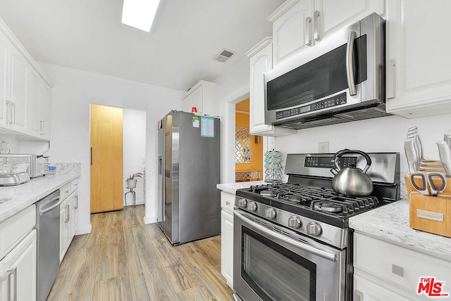 kitchen featuring light stone counters, light hardwood / wood-style floors, white cabinetry, and appliances with stainless steel finishes