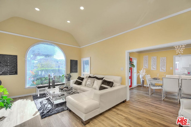 living room featuring vaulted ceiling, crown molding, and light hardwood / wood-style floors