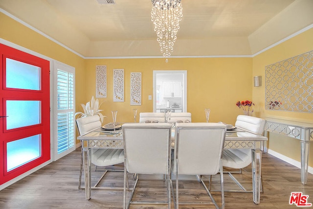 dining room featuring a chandelier, a raised ceiling, and hardwood / wood-style flooring