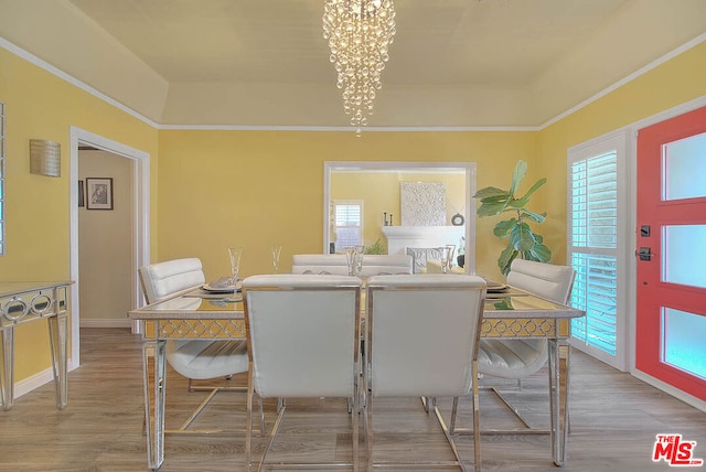 dining space with an inviting chandelier, a tray ceiling, and light hardwood / wood-style floors