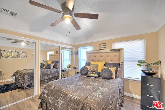 bedroom featuring ceiling fan, multiple windows, and light hardwood / wood-style floors