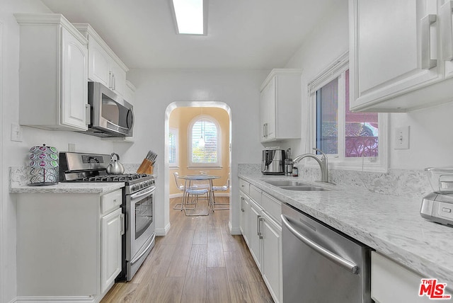 kitchen featuring appliances with stainless steel finishes, sink, white cabinetry, and light hardwood / wood-style flooring