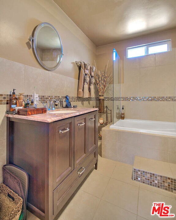 bathroom with vanity, tile walls, tile patterned floors, and tiled tub