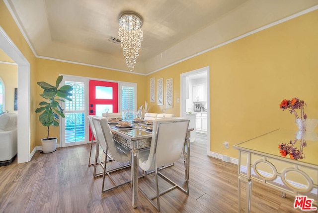 dining room with an inviting chandelier, a raised ceiling, and hardwood / wood-style floors