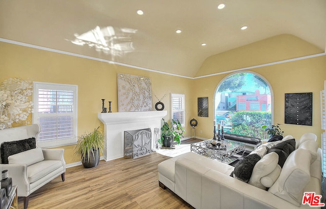 living room with light wood-type flooring, ornamental molding, and lofted ceiling