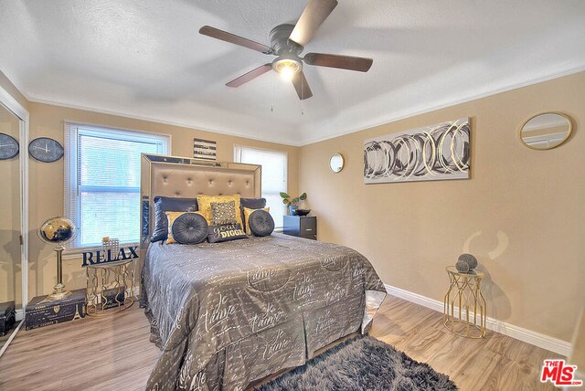 bedroom with ceiling fan, light hardwood / wood-style floors, a textured ceiling, and ornamental molding