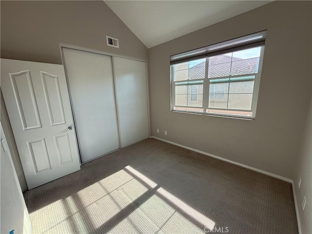 unfurnished bedroom featuring carpet, a closet, and vaulted ceiling