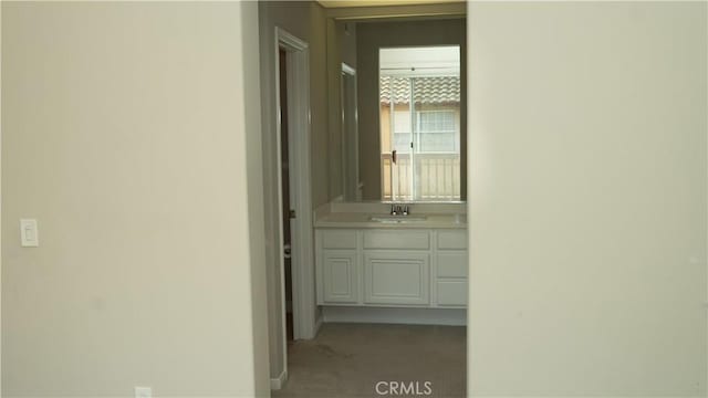 corridor with sink and light colored carpet