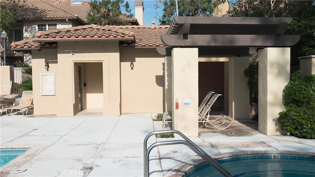 rear view of property featuring an in ground hot tub and a patio