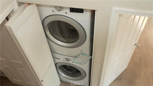 laundry room featuring light colored carpet and stacked washing maching and dryer