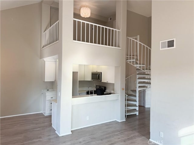 kitchen featuring light wood-type flooring, white cabinetry, range, and a towering ceiling