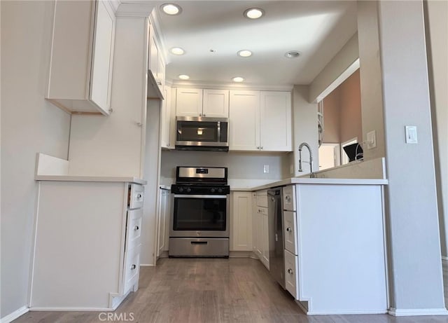 kitchen featuring wood-type flooring, appliances with stainless steel finishes, and white cabinetry