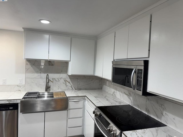 kitchen with white cabinetry, appliances with stainless steel finishes, decorative backsplash, tile counters, and sink