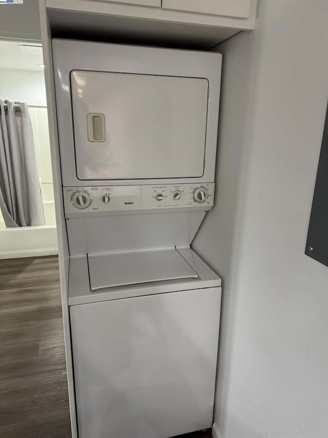 clothes washing area featuring dark hardwood / wood-style flooring and stacked washer / drying machine