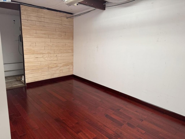 spare room featuring dark wood-type flooring and wood walls