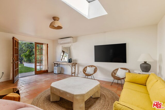 living room with light tile patterned floors, a skylight, french doors, and a wall unit AC