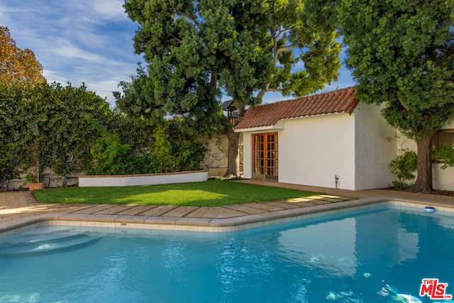 view of pool with an outbuilding and a lawn