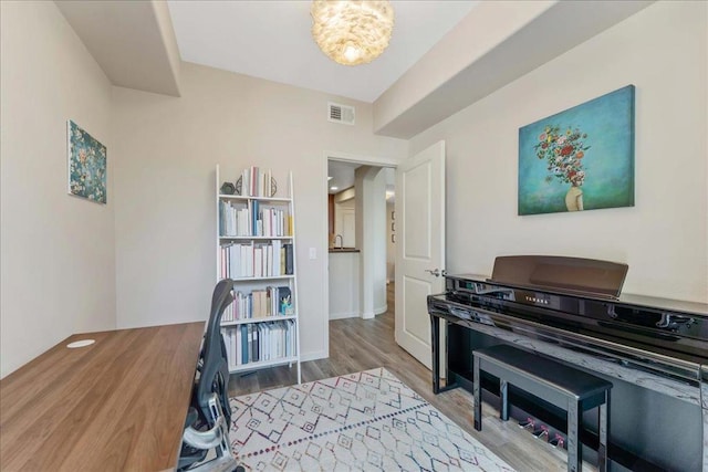 miscellaneous room featuring wood-type flooring and a notable chandelier