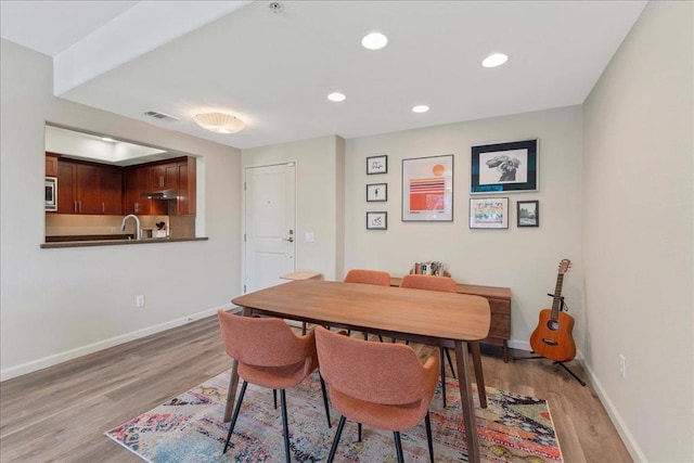 dining space with sink and light wood-type flooring