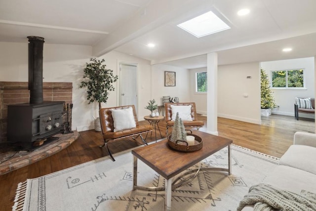 living room featuring lofted ceiling with beams, plenty of natural light, light wood-type flooring, and a wood stove