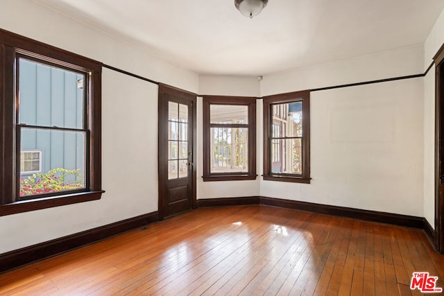 spare room with wood-type flooring and plenty of natural light