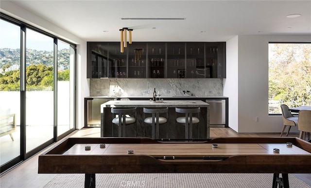 kitchen featuring stainless steel dishwasher, a kitchen island with sink, and tasteful backsplash