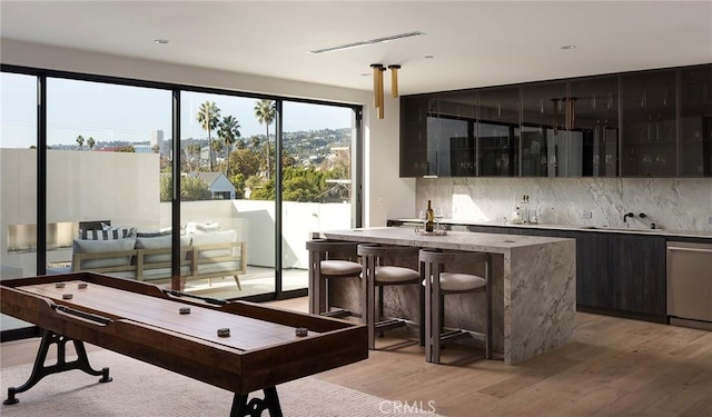 bar with sink, backsplash, stainless steel dishwasher, and light wood-type flooring